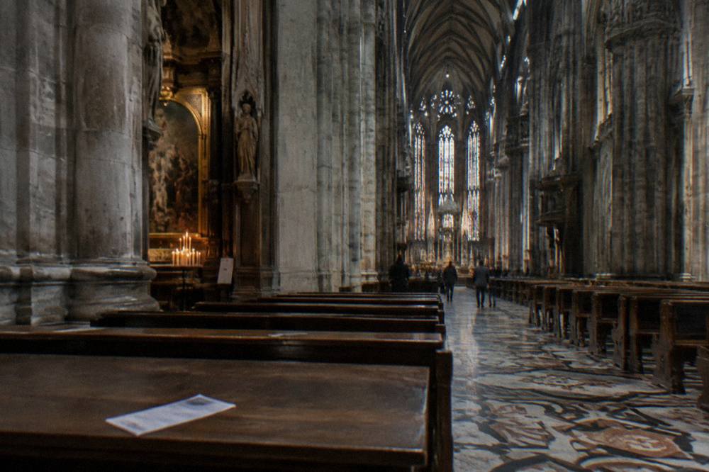 Interior of Milan Cathedral with tall gothic columns and stained glass windows