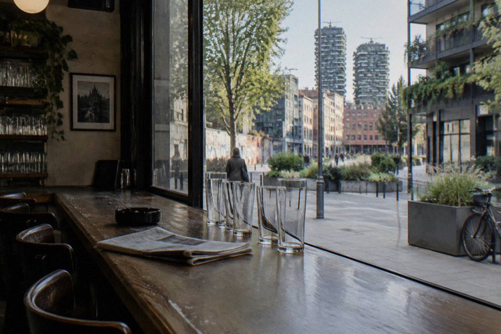 A quiet Milan bar interior with beer glasses lined up on a wooden counter