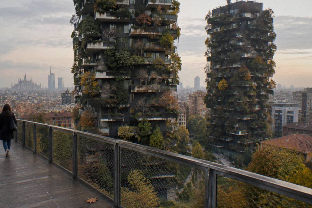 The Bosco Verticale towers seen from a public path with planted terraces visible on the facades