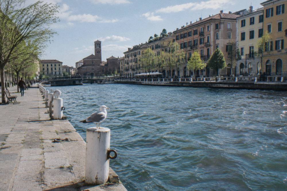 Tall canal-side buildings with wooden shutters above the water of the Naviglio Grande