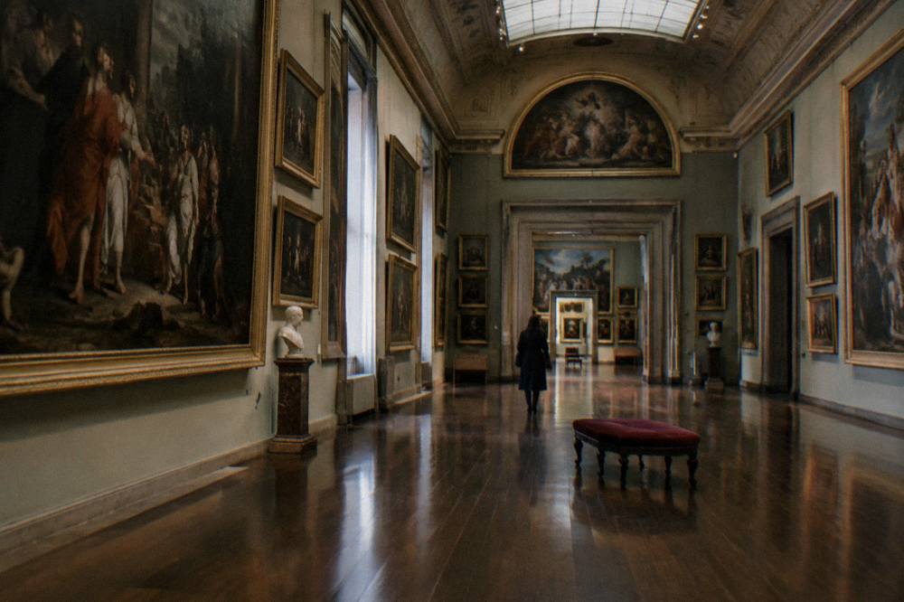 Grand Renaissance gallery hall with paintings hung floor to ceiling and polished wooden floors