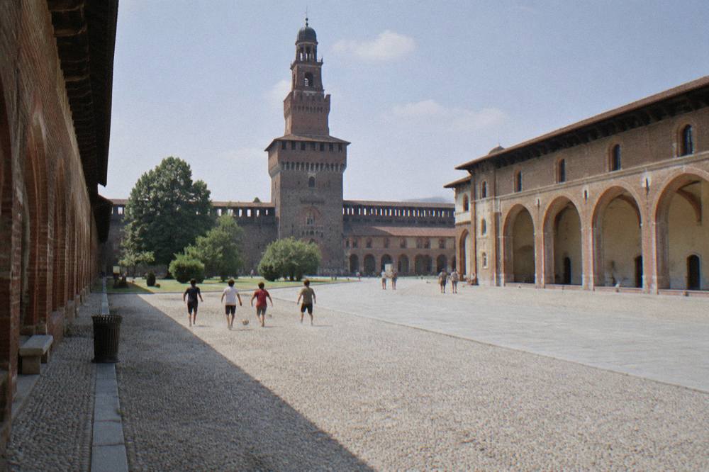 Wide stone courtyard inside Sforza Castle with arched walkways along the walls