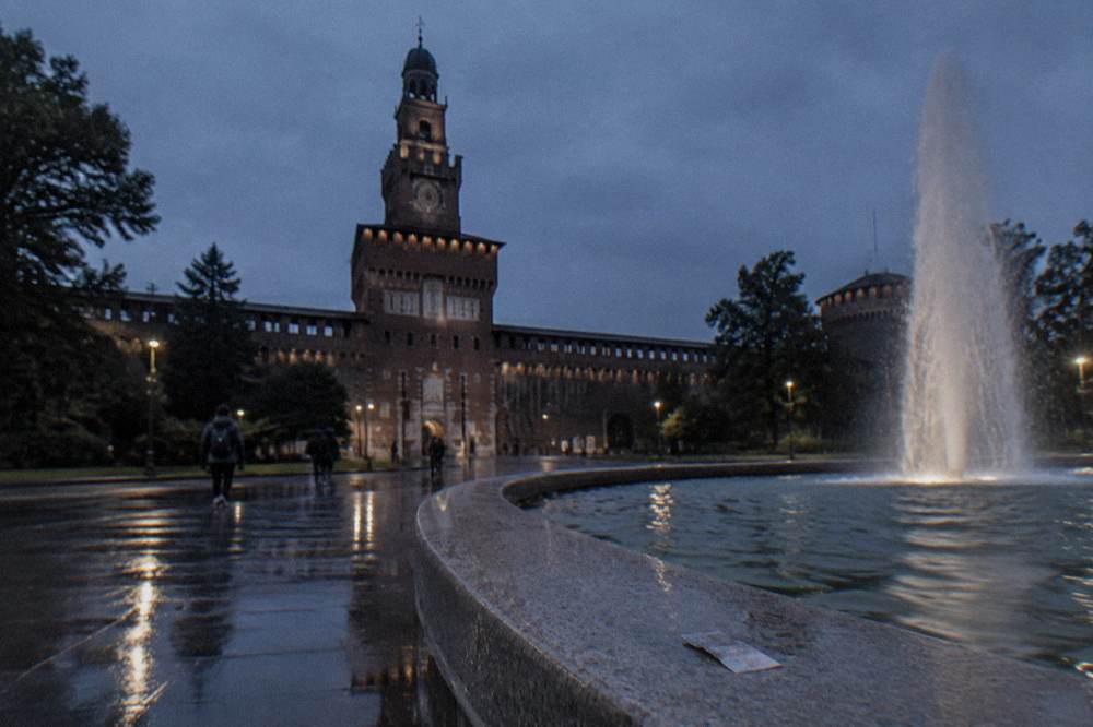 Fountain in Piazza Castello in front of the Sforza Castle tower at dusk