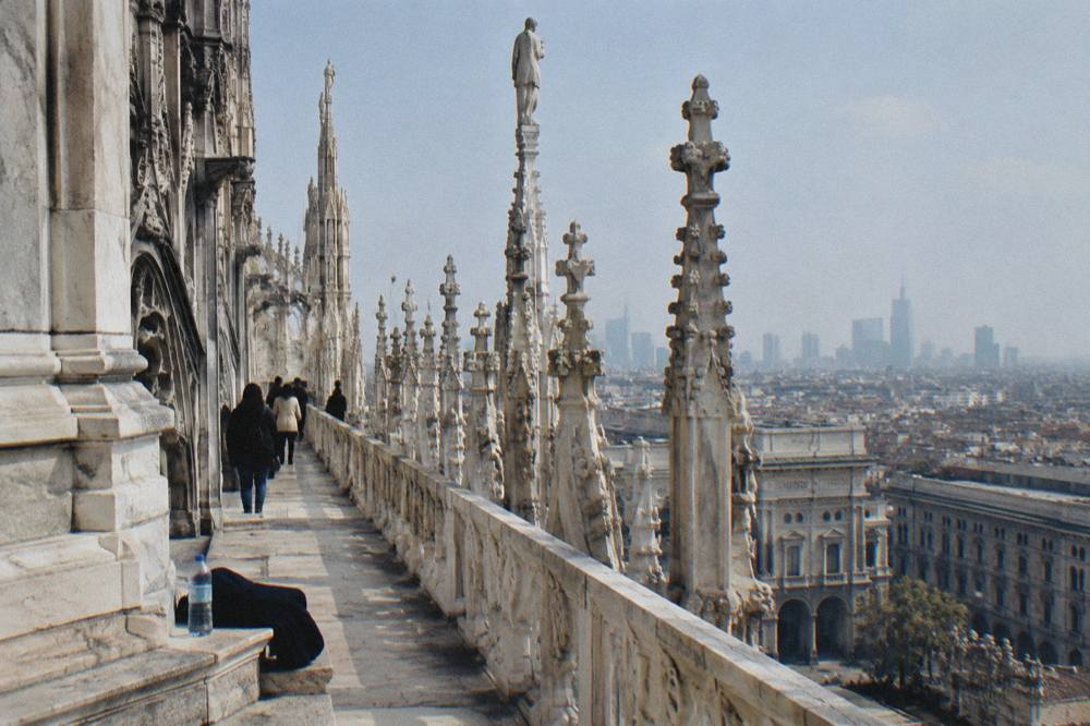 Marble rooftop terraces of Milan Cathedral with carved pinnacles and the city skyline beyond