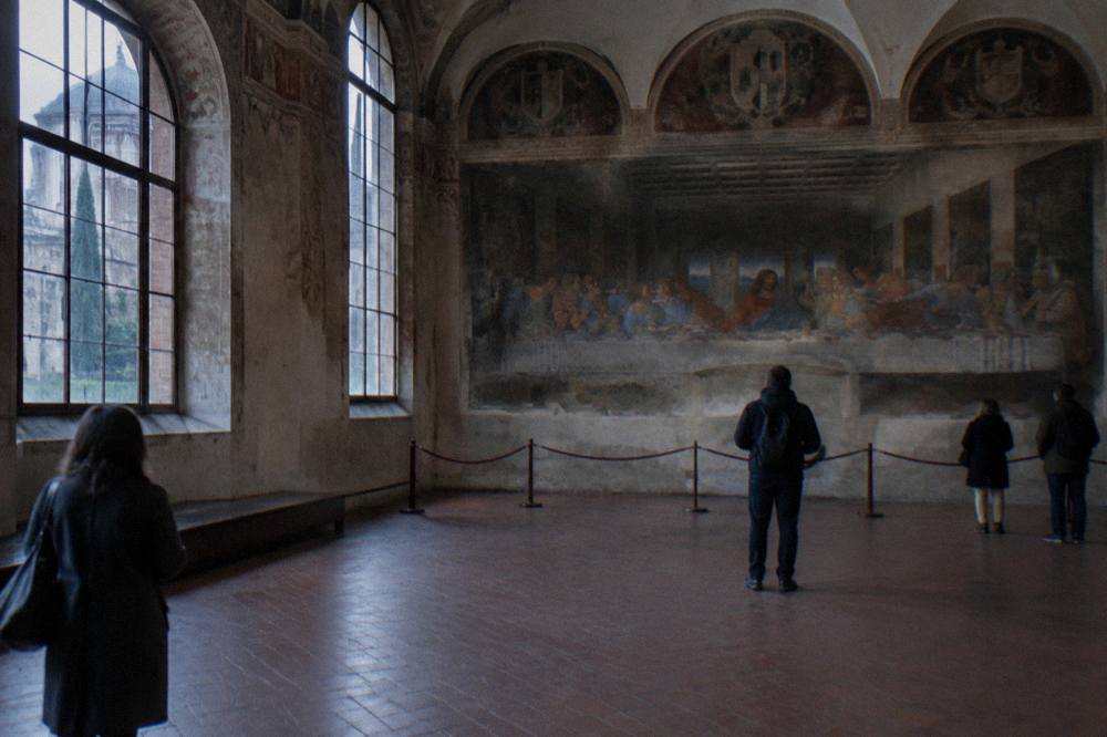 The interior of the Santa Maria delle Grazie refectory with the Last Supper fresco spanning the far wall between tall arched windows