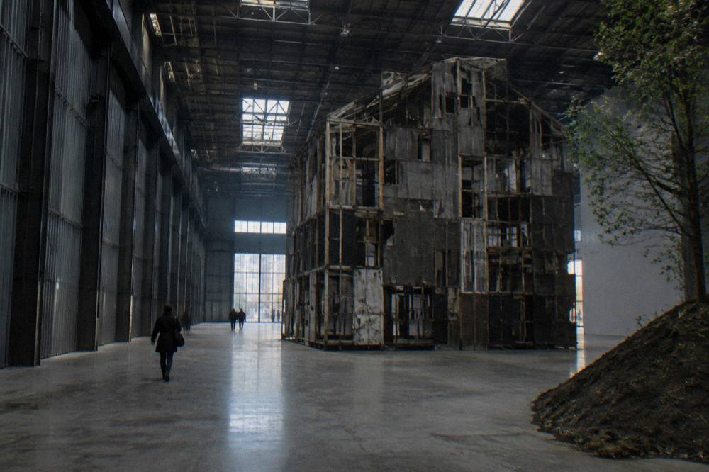 Wide industrial gallery hall with a large contemporary sculpture installation under a high ceiling