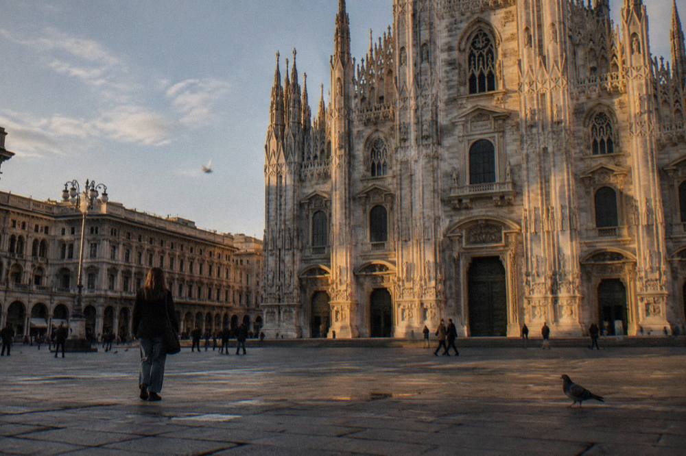 Marble facade of Milan cathedral seen from the open square in late afternoon light