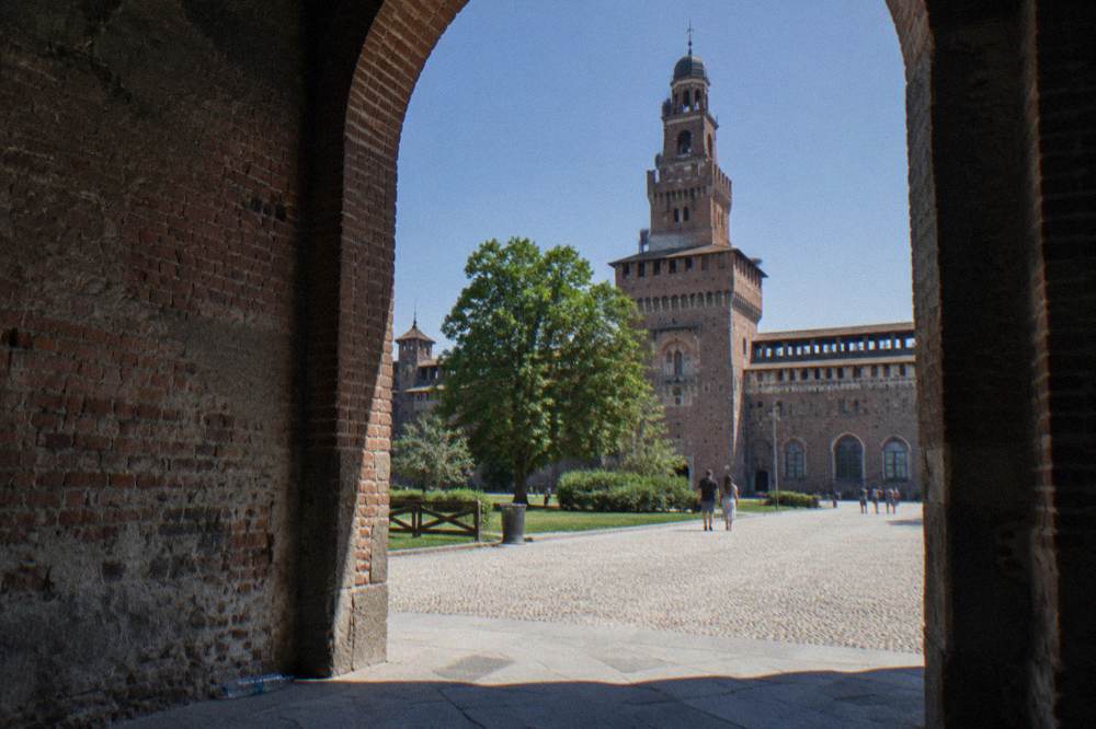 Brick tower and courtyard walls of Sforza Castle under a clear sky