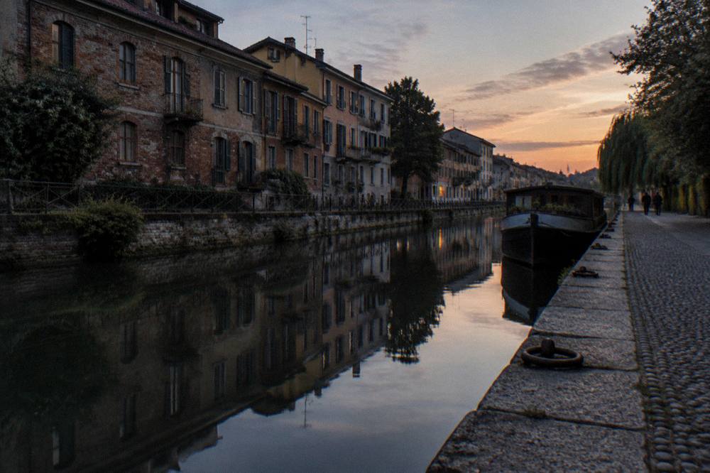 Canal side buildings reflected in the water of the Naviglio Grande at dusk