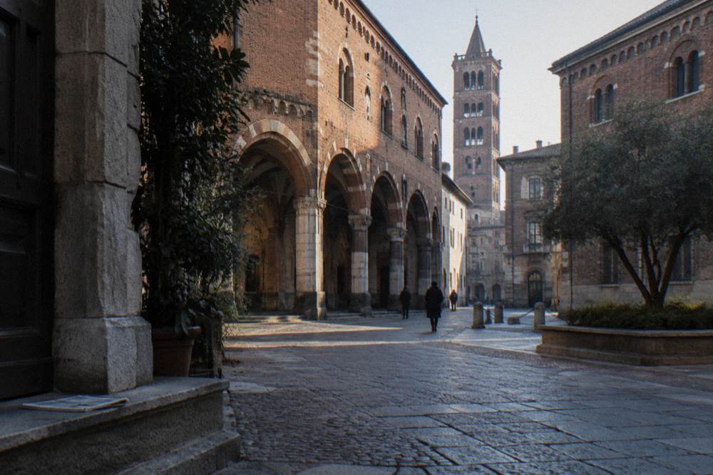 Cobblestone street with old buildings and a church tower in the background
