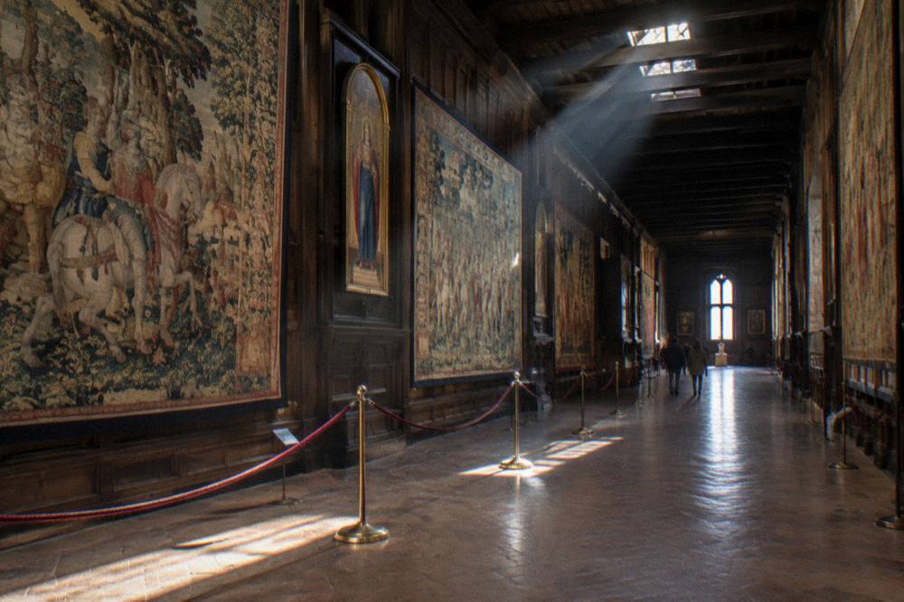 Gallery hall with paintings hung frame to frame under skylights
