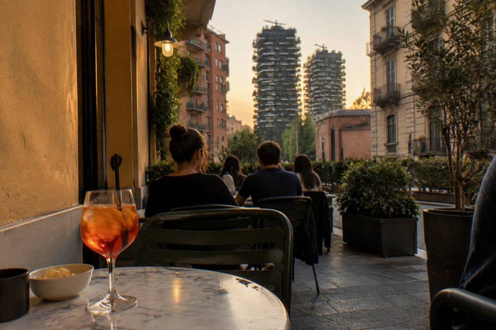 Evening light on a corner bar terrace in the Isola district with residents seated outside
