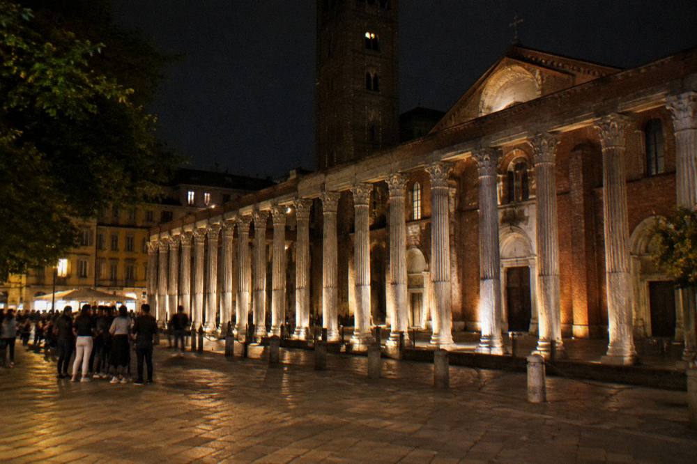 Illuminated columns and church facade beside a lamplit street at night