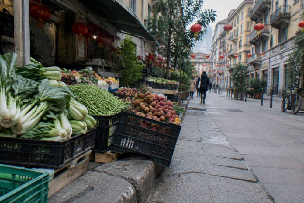 Market stall with boxes of fresh produce displayed on a Milan street pavement.