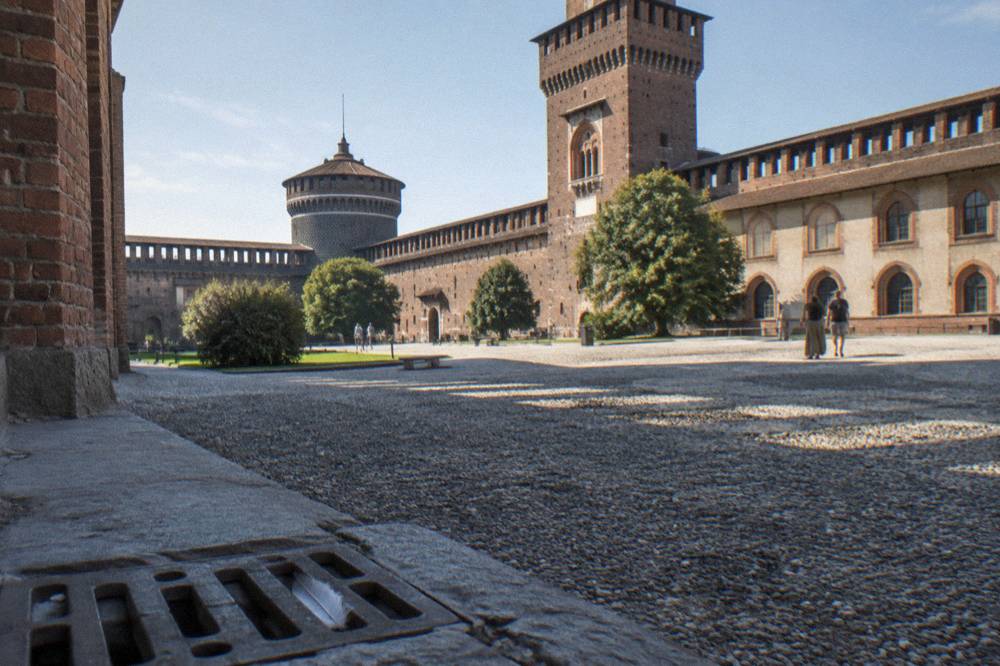 Sforza castle courtyard with brick towers and arches under open sky