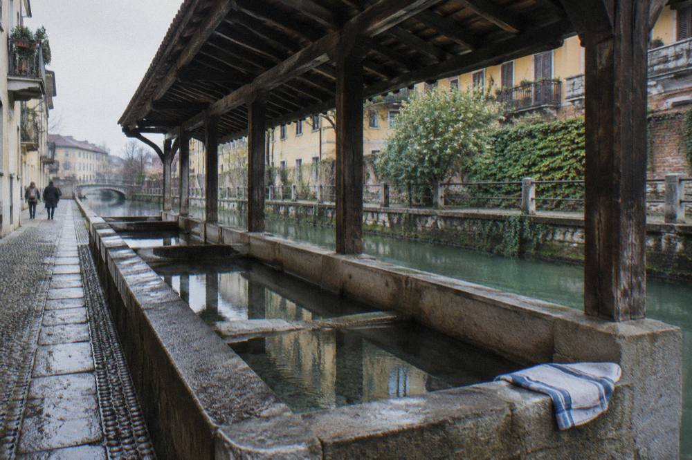 Old Milan canal lined with low brick buildings and stone bridge