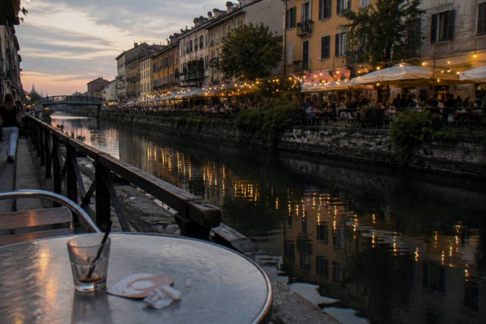 Canal-side bar terraces and string lights above the water at dusk
