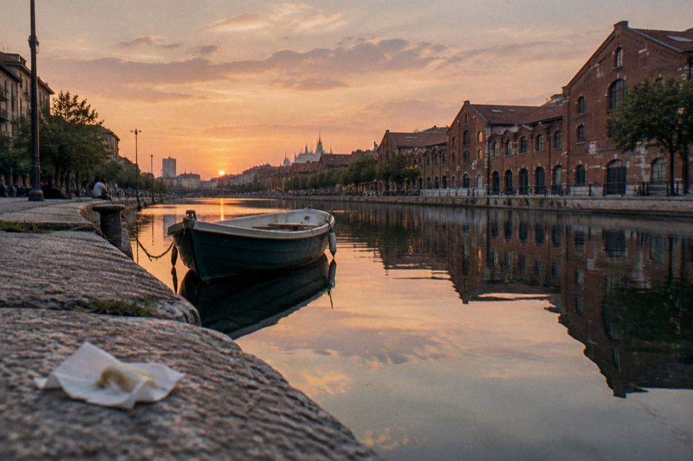 Stone dock edge at a Milan canal basin at sunset with still water