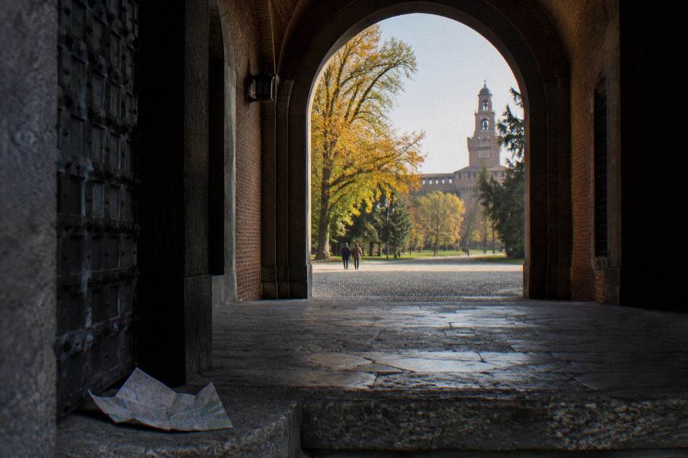 Visitors walking through the arched passage inside Sforza Castle toward the park entrance