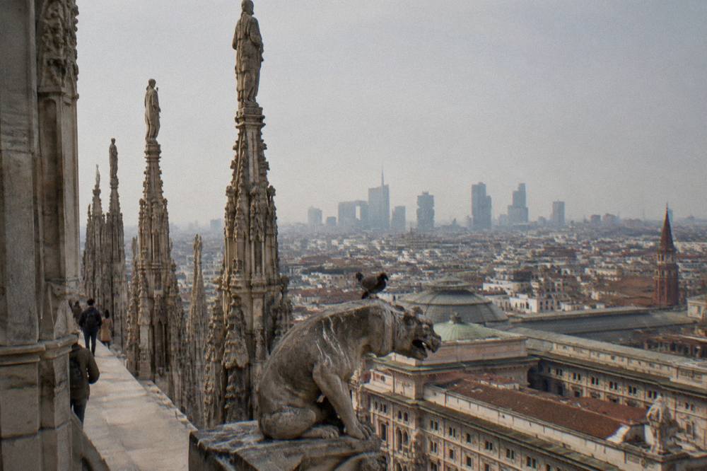Milan cathedral marble spires seen from the rooftop level against a pale sky