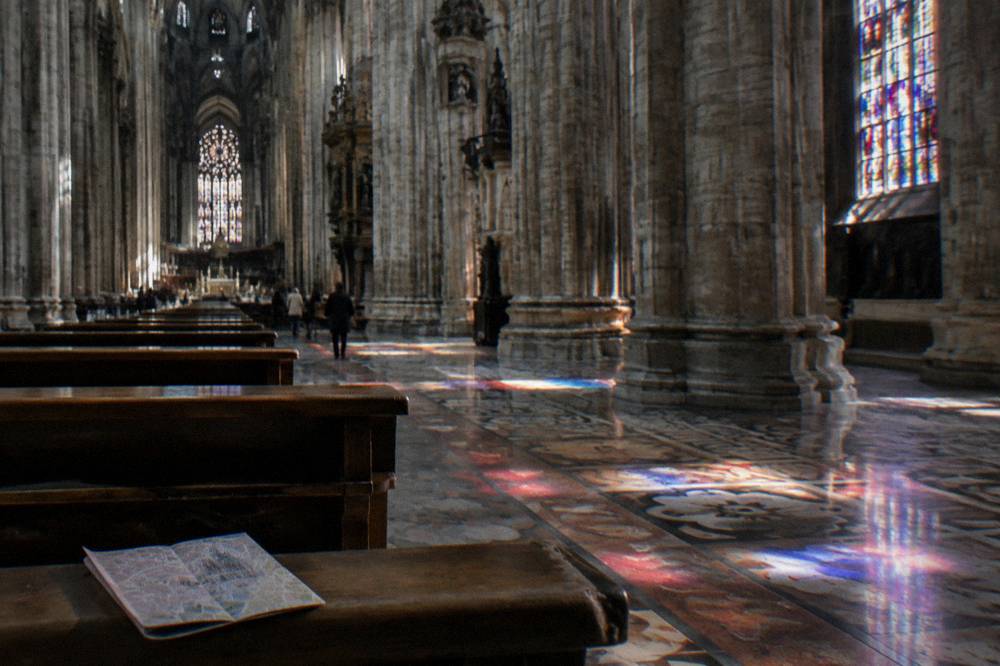Gothic cathedral interior nave with tall columns and stained glass light