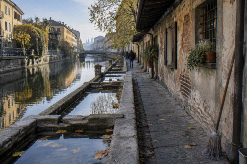 Canal-side street in the Navigli district with old brick buildings reflected in the water